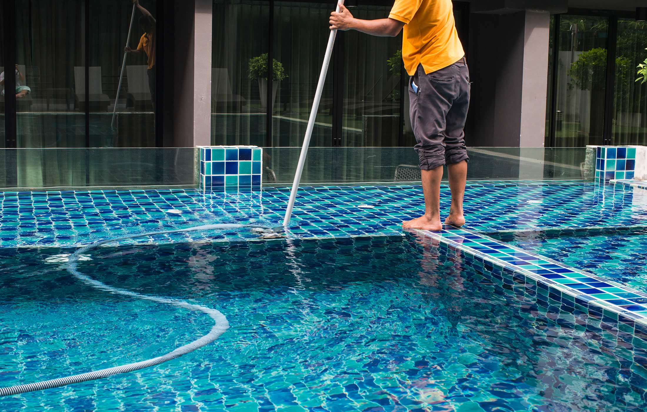 Photograph of a man cleaning a swimming pool, as captured from the Mango Property Management website