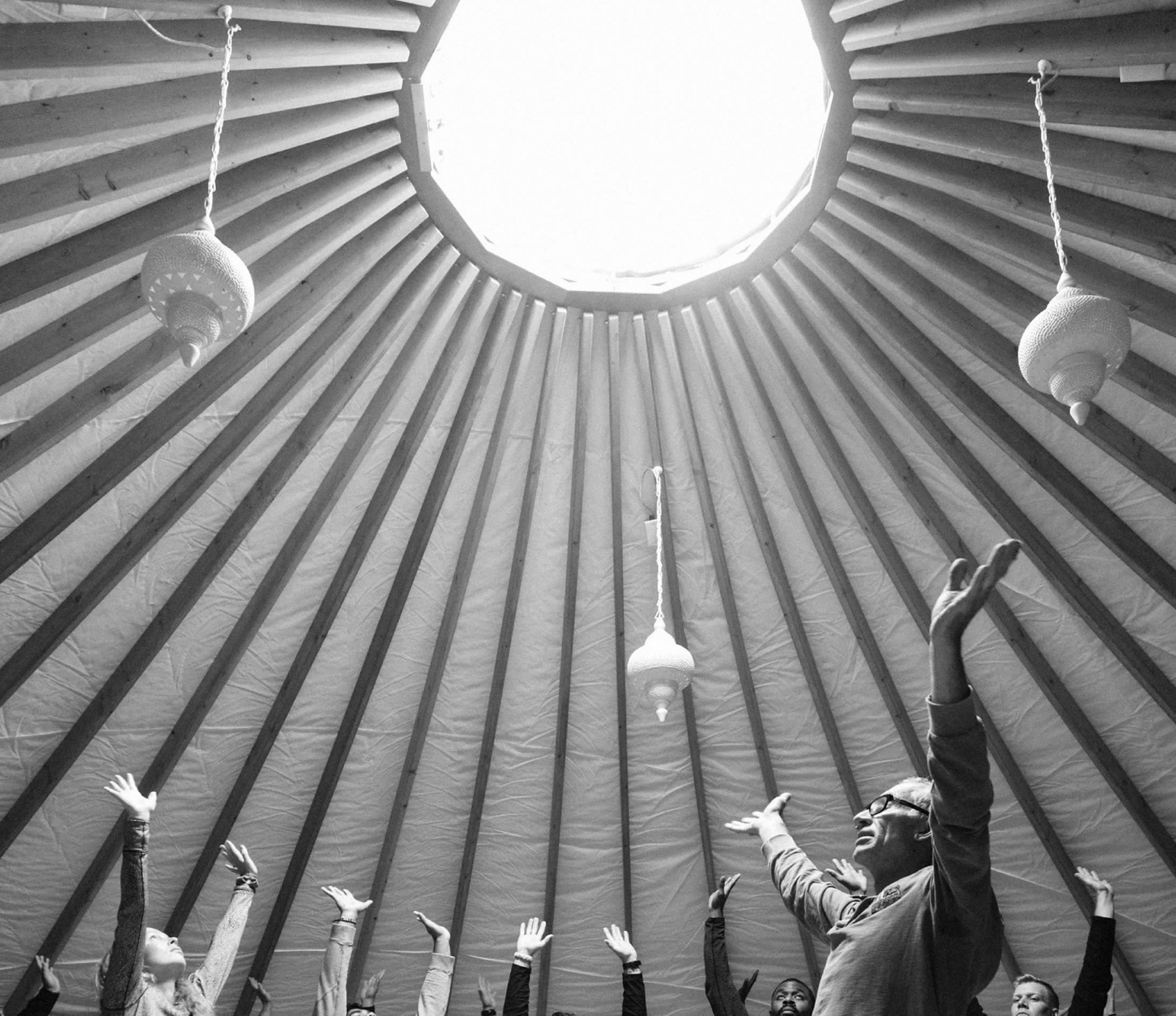 Grayscale photo of young adults with their arms raised toward the sky (upon completion of a yoga session)